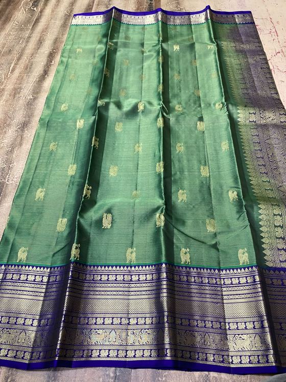 Bottle green silk saree with gold animal motifs and a royal blue zari border